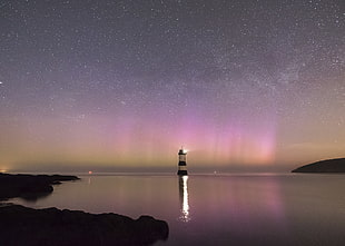 lighthouse surrounded calm body of water under starry nights, penmon, anglesey HD wallpaper