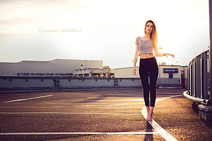woman wearing gray top and black leggings standing on concrete ground