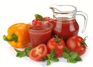drinking glass and pitcher filled with red liquid near bell peppers and tomatoes