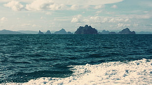 photo of black islands near ocean photo taken during daytime HD wallpaper