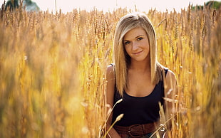 blonde haired woman wearing black sleeveless top surrounded with brown hay