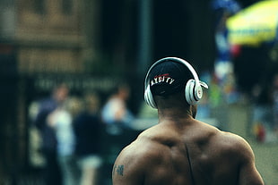 shallow focus photography of topless man wearing white headphones