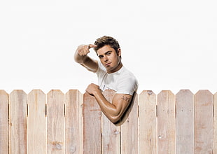 Zac Efron leaning on brown wooden fence