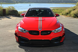 red BMW car parked near body of water HD wallpaper