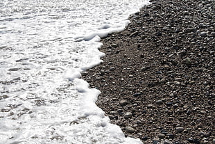 white ocean wave beside brown rocky sand photography