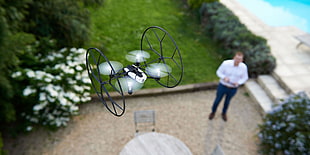 person controlling the white and black mini-drone during daytime