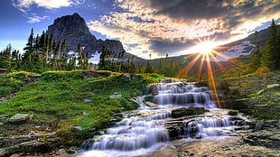 waterfalls between green grasses during sunrise