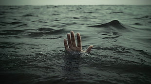 person underwater raising right hand, water,  death, drowning