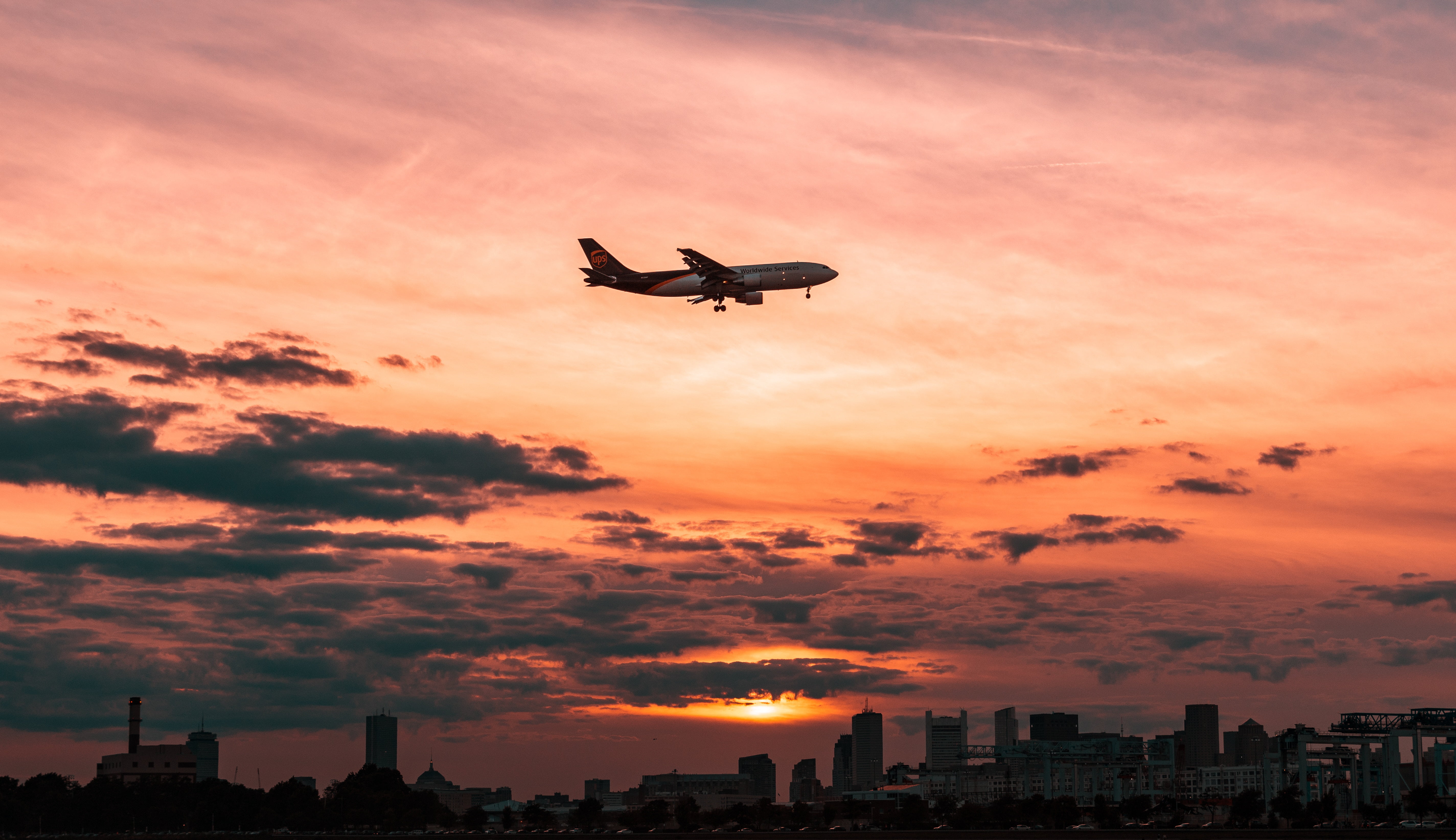 airplane flying over buildings with orange sky