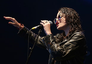 woman wearing black leather jacket and sunglasses holding microphone