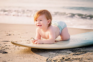 baby laying on white surfboard