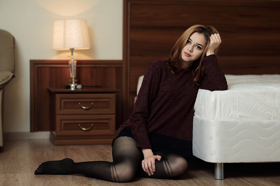 woman wearing brown sweater and black stockings leaning on white bed HD wallpaper