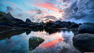 landscape photography of body of water beside gray rock formation
