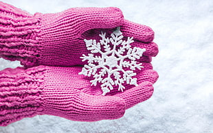 person wearing pink gloves with white snowflakes