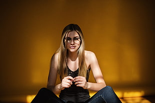 woman wearing black lace tank top sitting near brown wall