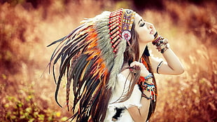 photo of a woman closing her eyes wearing black and brown Native American headdress