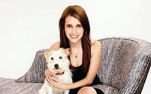 woman in black tank top holding long-coated white dog