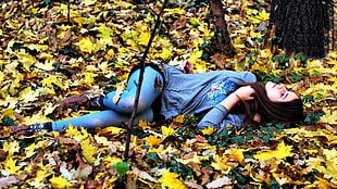 woman wearing black hijab, blue long-sleeve shirt and blue leggings laying on maple leaves