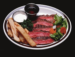 French Fries and bbq meat with sliced vegetable both on round white ceramic plate