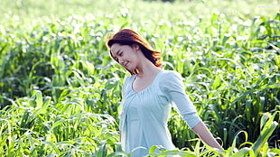 woman in gray elbow-sleeved top in field with green leaf plants during daytime