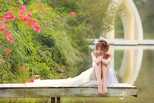 woman wearing white wedding dress sitting on white wooden boat deck
