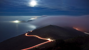 time lapse photography of vehicle lights surrounding mountain, coast, nature, clouds, road