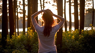 woman wearing white shirt facing sunrise in woods