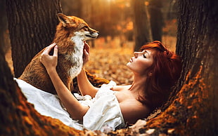 woman lying on tree trunk with red fox