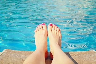 woman's feed on brown rug in front of the body of water HD wallpaper