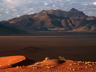 sand open field beside rocky mountain at daytime HD wallpaper
