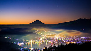 painting of city near mountains and body of water with lights at night