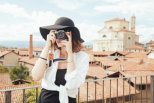 woman wearing white long-sleeved shirt using black bridge camera
