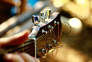 shallow focus photography of person holding black guitar headstock