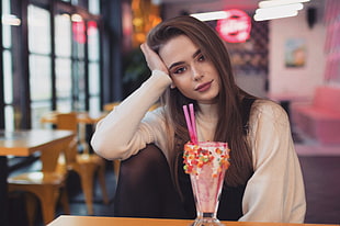 woman wearing white and black long-sleeved top holding her hair in front of ice cream