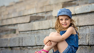 shallow focus photography of blonde haired girl wearing blue cap and dress