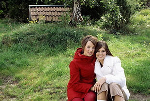two woman wearing red and white jacket during day time