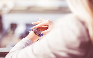 woman wearing gray long-sleeved top and round analog watch