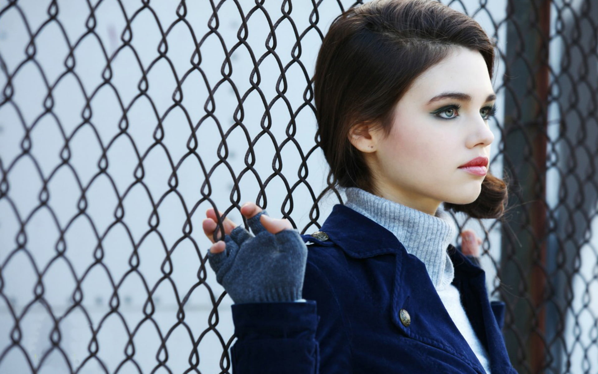 woman in blue suede winter clothes with cyclone fence