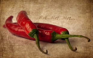 three red chili peppers on beige surface
