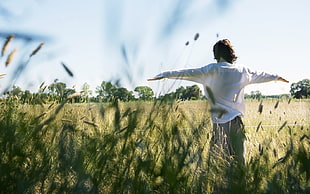 woman wearing white shirt spreading her arms in grass field