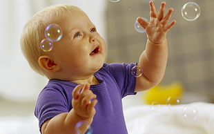 toddler in purple shirt playing with bubbles