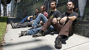 four men sitting on gray concrete floor