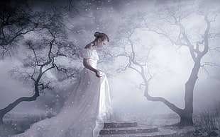 woman in white dress walks between two trees