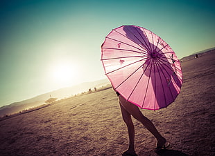 woman standing while holding pink folding umbrella