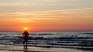 silhouette of woman near the seashore during sunset