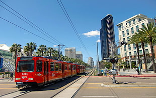red train near the high-rise building in daytime photo