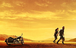 couple walking near black touring motorcycle during orange sunset