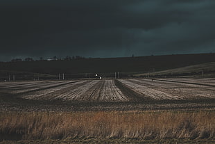 photo of gray open field during dark cloudy day