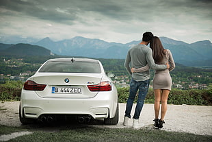 woman and man hugging each other beside white BMW car