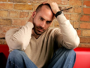 man in beige sweater holding his neck and head